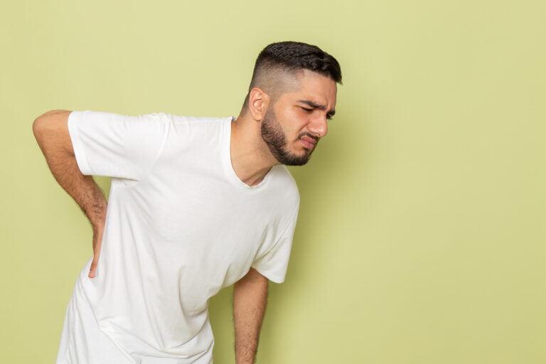 Young man holding his lower back in pain, illustrating kidney stone symptoms and flank pain